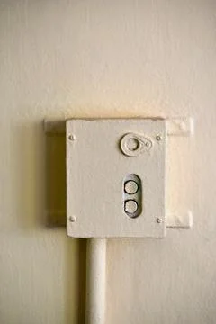 An old iron start and stop relay on the wall. An iron box with buttons in a m Stock Photos