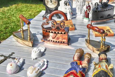 Old irons and various plaster figurines on open air market Photos