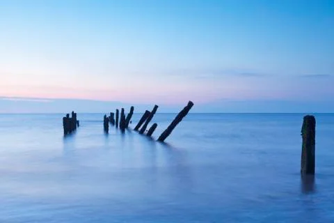 Old jetty posts at sunrise Stock Photos