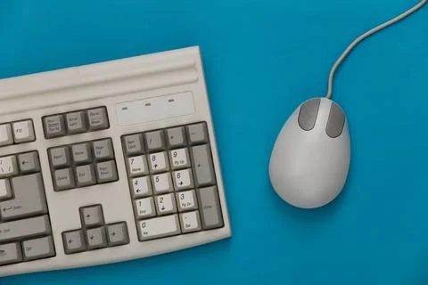 Old keyboard and pc mouse on a blue background. Top view. Flat lay 스톡 사진