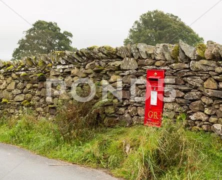 Old king george red post box in stone wall Stock Photos