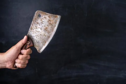 Old kitchen cleaver in the chef's hand on a dark background Stock Photos
