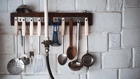 Old kitchen ware hanging on the white wall.Toned image. Foto stock