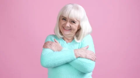 Old lady candid self cuddle shoulders arms isolated pastel color background Stock Footage 169288511