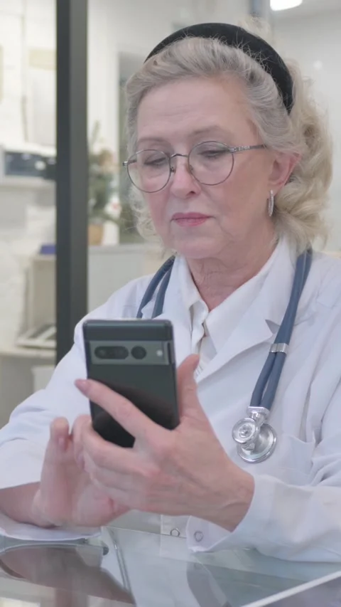 Old Lady Doctor Using Phone in Clinic, vertical video Video stock 325567223