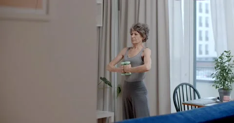 Old lady is doing energizing dumbbell exercises at home, fitness training for Stock Footage 232225438