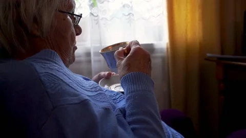 Old lady drinking tea while sitting next to the window	 Stock Footage 133053238