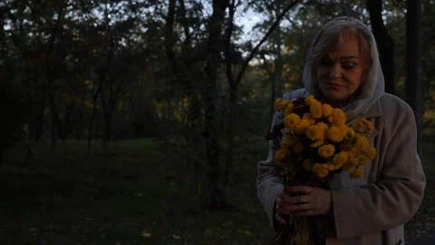 Old lady goes through park with flowers Stock Footage 118257524