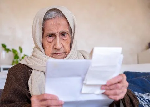 Old lady holding receipt checking costs of living and house rent and her debt Stock Photos