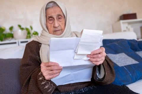 Old lady holding receipt checking costs of living and house rent and her debt Stock Photos