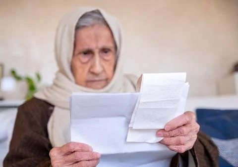 Old lady holding receipt checking costs of living and house rent and her debt Foto stock