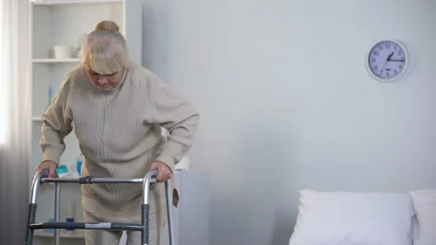 Old lady learning to walk with frame, rehabilitation after hip joint replacement Stock Footage 102418005