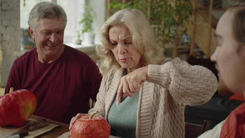 An old lady learns to carve a pumpkin for halloween with her family Stock Footage 163020247