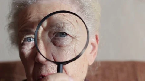 Old lady looking through a magnifying glass Stock Footage 83324650