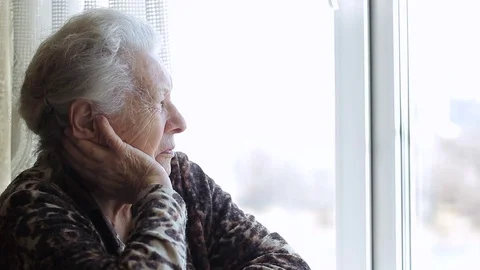 The old lady looks out the window. Video stock 73305037