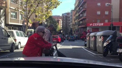 Old lady in read coat walking across in front of car windshield Stock Footage 57562429