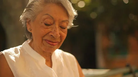 An old lady sits at a bench and enjoys her tablet Video stock 33889462