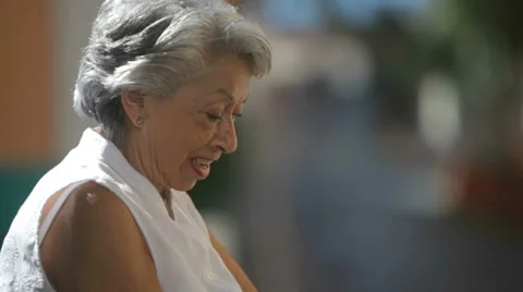 An old lady sits on a park bench and uses her tablet computer Vidéo 33889386