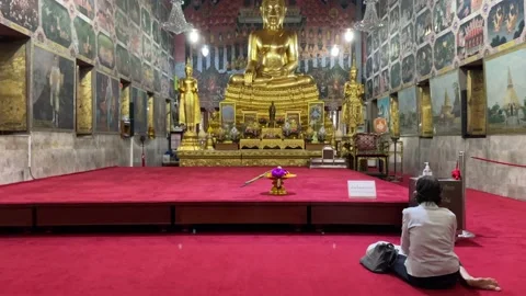 Old lady sitting on floor with red carpet praying to golden buddha Video stock 202917401