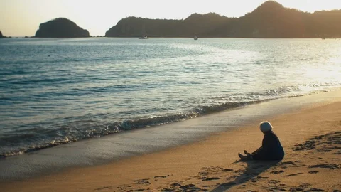 Old lady sitting on sandy beach Stock Footage 119114290