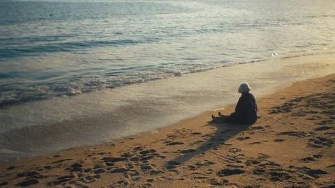 Old lady sitting on sandy beach Stock Footage 119114927