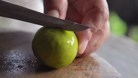 Old lady using knife for cutting green lemon above wooden board. Stock Footage 114653628