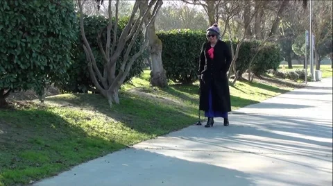 Old Lady Walking Picks Up Something Off Ground and Puts in Pocket Vídeo Stock 59971956