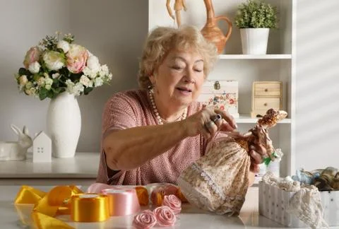 Old lady is working on creating a doll in her workshop Фото
