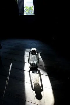 Old lantern casts light in dark rustic room 写真素材