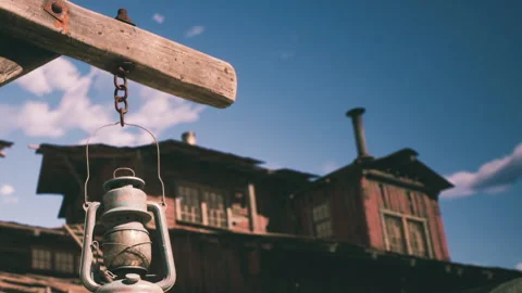 Old lantern hanging in front of a rustic wooden building under a blue sky Video stock 344406266