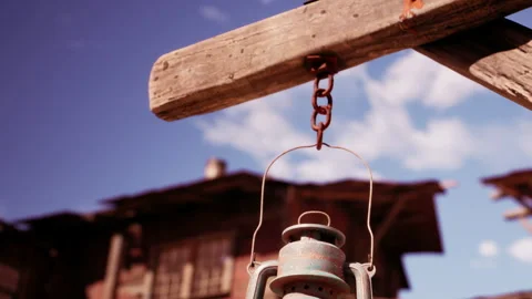 Old lantern hanging on a wooden post under a blue sky with clouds Video stock 344409060