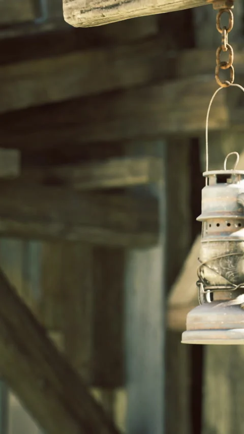 Old lantern hangs gracefully in rustic wooden setting during soft daylight Stock Footage 331841210