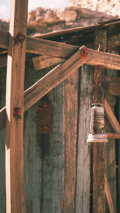Old lantern hangs on wooden structure near green wooden wall Stock Footage 339041083