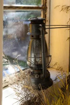 Old lantern resting on a windowsill inside an old house Foto stock