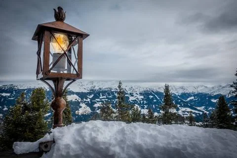 An old lantern stands on a railing and in the background are the snow-cove... Stock Photos