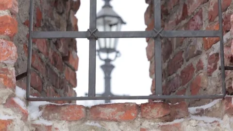 The old lantern in the window of an ancient castle through the grate, snowstorm. Video stock 72935026