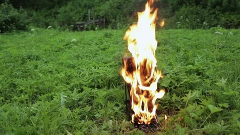 Old leather black high punk women's boots burn with fire standing on the grass Stock Footage 110777212