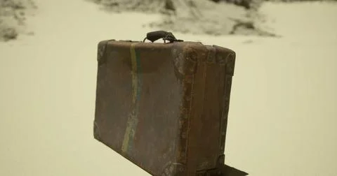Old leather suitcase resting on sandy surface in deserted area during dayligh Stock Illustration