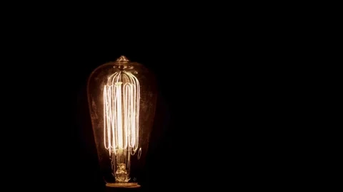 Old light bulb filament glows and dims in darkness 動画素材 329666922