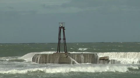 Old light on seawall having waves wash over it Stock Footage