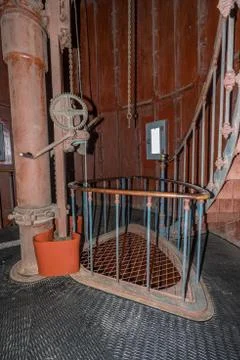 Old lighthouse on the inside. Red iron spiral stairs, round window and blue w Stock Photos