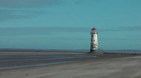 Old lighthouse at low tide sand blowing in foreground Stock Footage 47076949