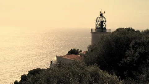 Old lighthouse on a pine cliff against the backdrop of a sparkling sea. Stock Footage 121803951