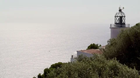 Old lighthouse on a pine cliff against the backdrop of a sparkling sea. Stock Footage 121804655