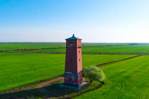 Old lighthouse with red stripes in spring field. Scenic landscape  Stock Photos