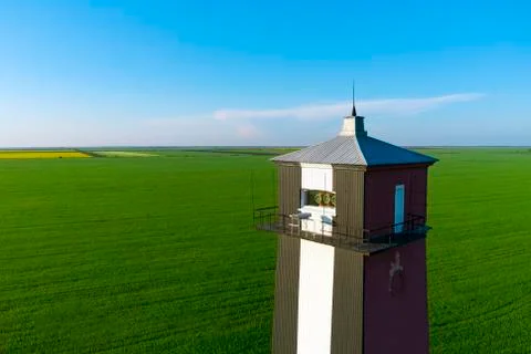 Old lighthouse with red stripes in spring field. Scenic landscape  Stock Photos