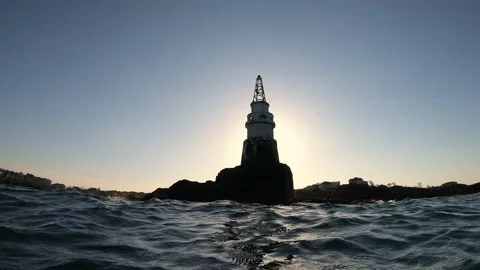 Old lighthouse on a rocky shore at sunset Stock Footage 130844680