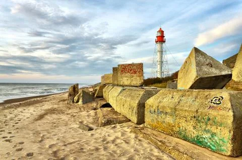 Old lighthouse at the sunset with large rocks on a foreground 写真素材