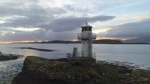 Old lighthouse at sunset overlooking mountains and islands Stock Footage 102412502