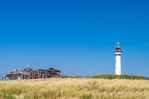 An old lighthouse tower on a coastal dune with sea grass. Stock Photos